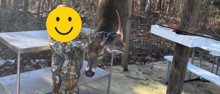 Young hunter with face covered by a smiley beside a hanging deer Young hunter with face covered by a smiley beside a hanging deer